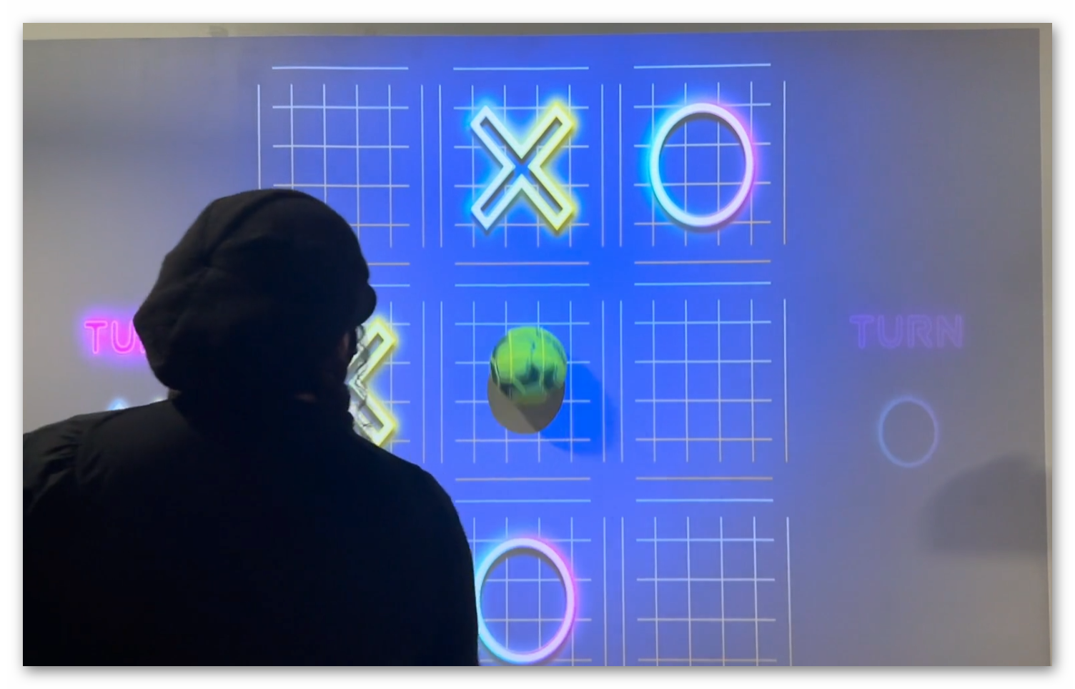Children playing Tic Tac Toe by throwing balls at interactive wall projection